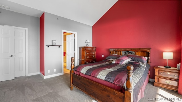 carpeted bedroom featuring lofted ceiling and ensuite bath