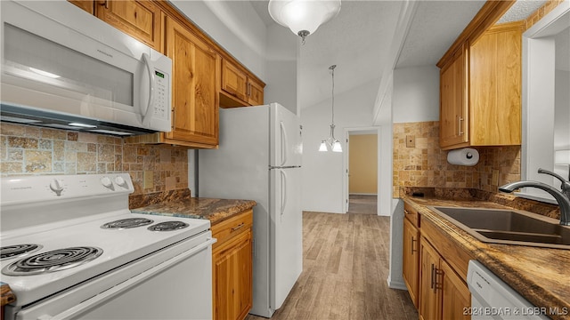 kitchen featuring hanging light fixtures, backsplash, white appliances, hardwood / wood-style flooring, and sink