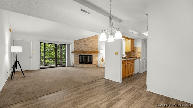 unfurnished living room featuring wood-type flooring, a textured ceiling, a notable chandelier, lofted ceiling, and a fireplace