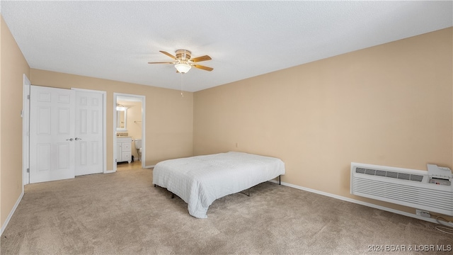 carpeted bedroom featuring connected bathroom, a wall unit AC, ceiling fan, and a textured ceiling