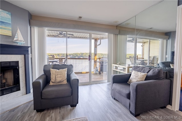 living room featuring hardwood / wood-style floors, ceiling fan, a fireplace, and plenty of natural light