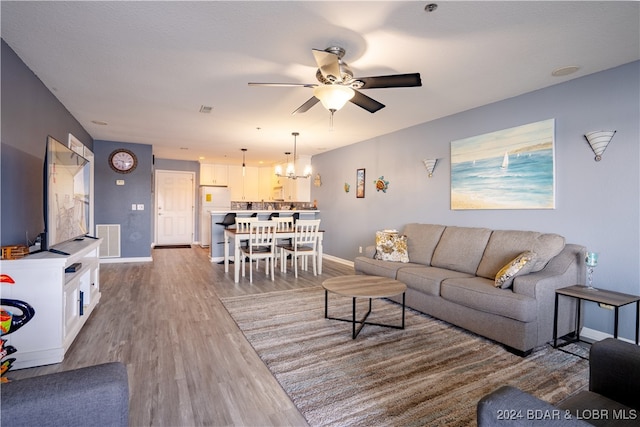 living room featuring hardwood / wood-style flooring and ceiling fan with notable chandelier