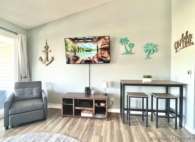 interior space with a textured ceiling, a wealth of natural light, vaulted ceiling, and hardwood / wood-style flooring