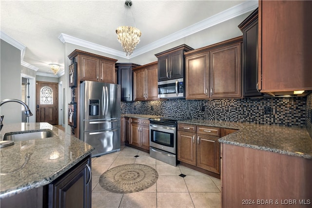 kitchen with stainless steel appliances, crown molding, dark stone counters, sink, and a chandelier