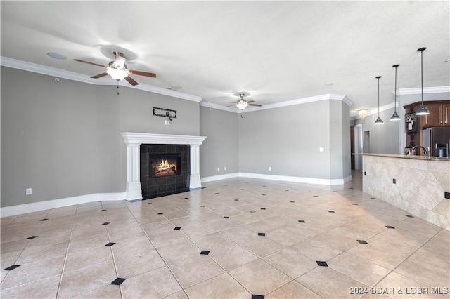 unfurnished living room with ceiling fan, a tile fireplace, and crown molding