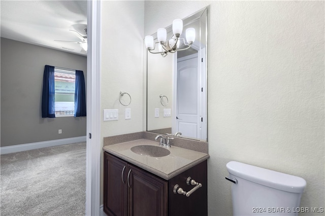 bathroom featuring ceiling fan with notable chandelier, vanity, and toilet