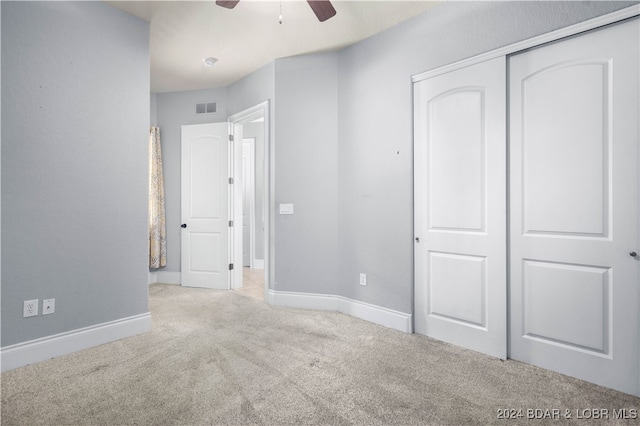 unfurnished bedroom with ceiling fan, light colored carpet, and a closet