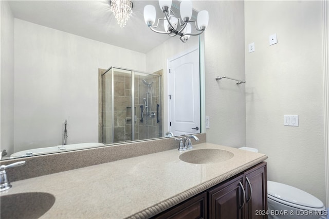 bathroom with a notable chandelier, vanity, a shower with shower door, and toilet