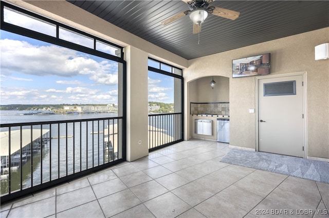 unfurnished sunroom featuring ceiling fan, a water view, and wooden ceiling