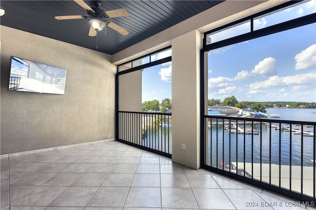 unfurnished room with wood ceiling, a water view, light tile patterned flooring, and ceiling fan