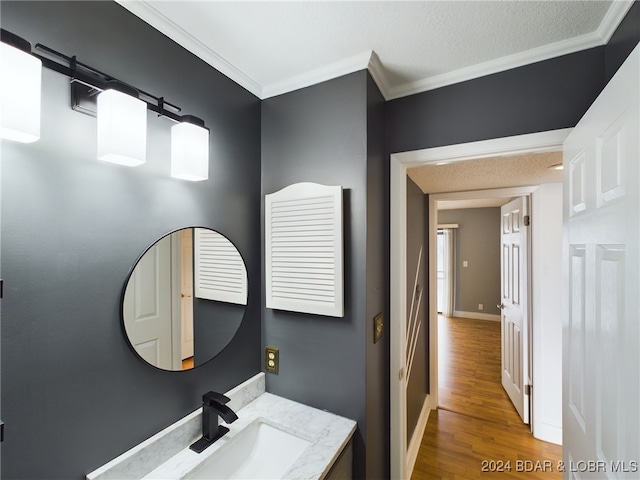 bathroom featuring ornamental molding, vanity, a textured ceiling, and hardwood / wood-style floors