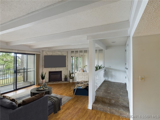 living room with beamed ceiling, a fireplace, hardwood / wood-style floors, and a textured ceiling