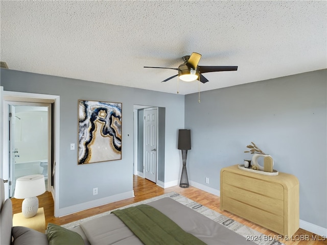 bedroom with light hardwood / wood-style flooring, connected bathroom, ceiling fan, and a textured ceiling