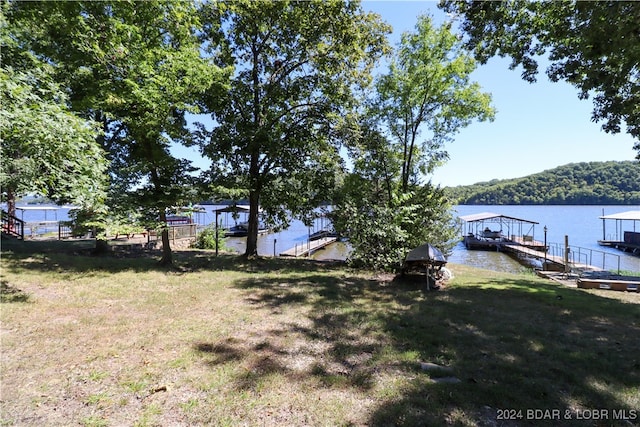 view of dock with a lawn and a water view