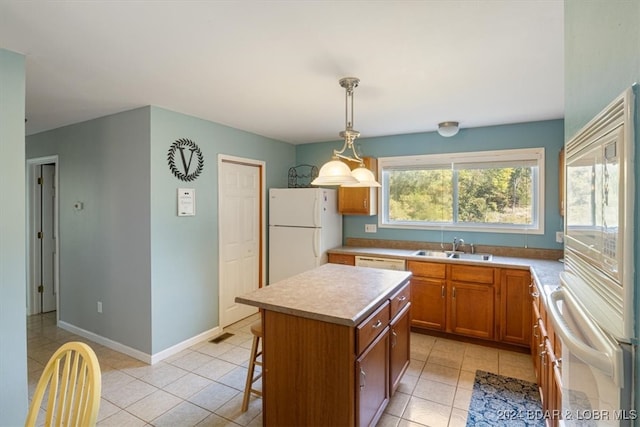 kitchen featuring a breakfast bar area, a kitchen island, white appliances, light tile patterned floors, and decorative light fixtures