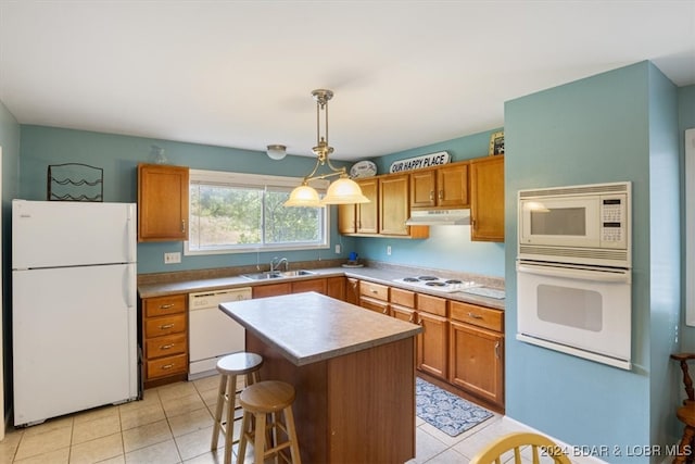 kitchen featuring sink, a kitchen island, white appliances, light tile patterned floors, and decorative light fixtures