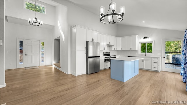 kitchen featuring a kitchen island, high vaulted ceiling, white cabinetry, stainless steel appliances, and light wood-type flooring