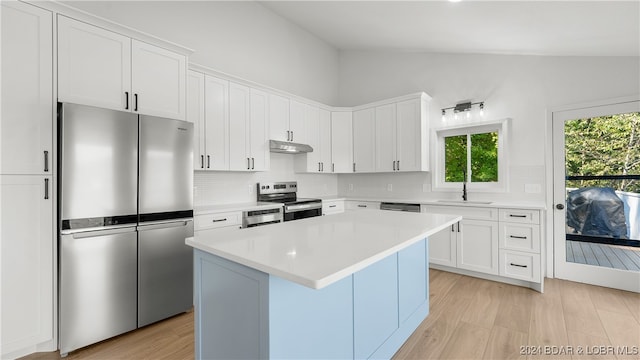 kitchen featuring stainless steel appliances, white cabinetry, lofted ceiling, and a kitchen island