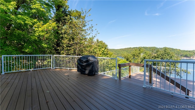 wooden deck featuring a water view and a grill