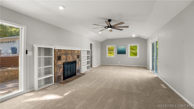 unfurnished living room with a wealth of natural light, vaulted ceiling, ceiling fan, and a fireplace