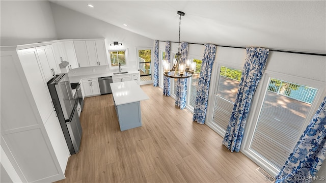 kitchen with pendant lighting, a chandelier, lofted ceiling, white cabinetry, and stainless steel dishwasher