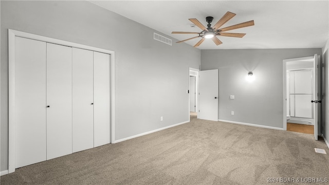 unfurnished bedroom featuring light carpet, a closet, lofted ceiling, and ceiling fan