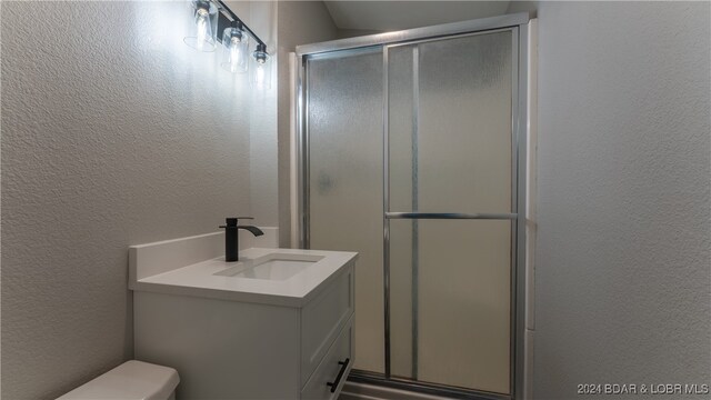 bathroom featuring vanity, toilet, and a shower with shower door