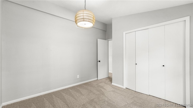 unfurnished bedroom featuring light colored carpet and a closet