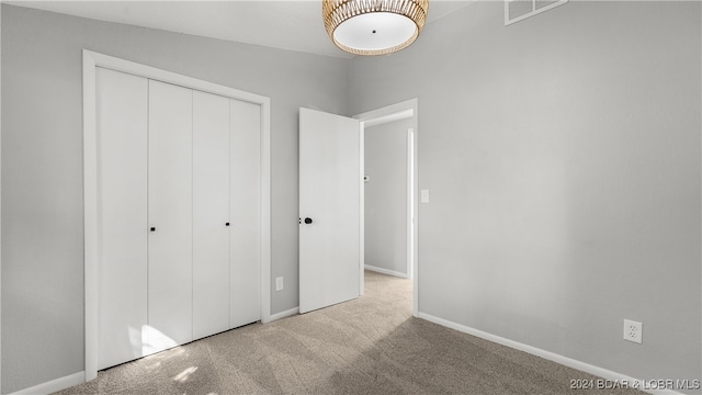 unfurnished bedroom featuring light colored carpet and a closet