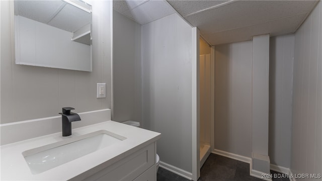 bathroom with walk in shower, a paneled ceiling, and vanity