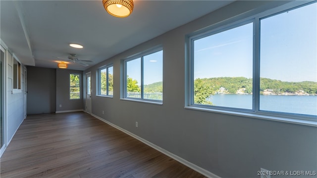 interior space with wood-type flooring, a water view, and ceiling fan