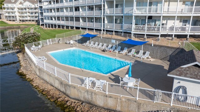 view of swimming pool featuring a patio and a water view