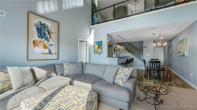 living room featuring an inviting chandelier, a towering ceiling, and hardwood / wood-style flooring