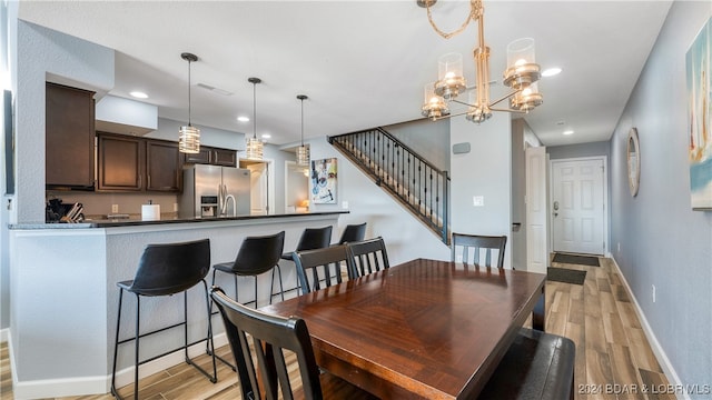 dining space featuring light wood-type flooring and a notable chandelier