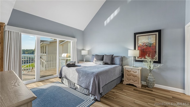 bedroom featuring light hardwood / wood-style floors, access to exterior, and high vaulted ceiling