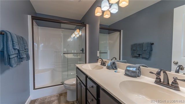 bathroom with hardwood / wood-style flooring, vanity, toilet, and an enclosed shower