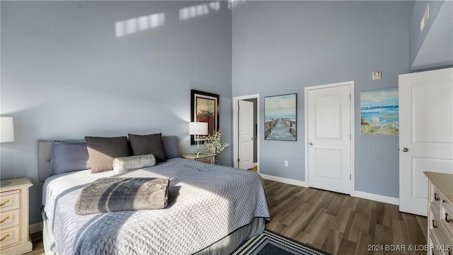 bedroom with a towering ceiling and dark wood-type flooring