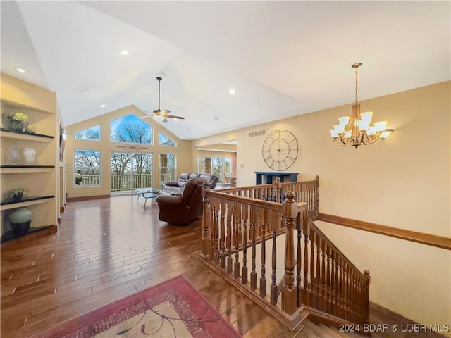 living room with vaulted ceiling, built in shelves, wood-type flooring, and ceiling fan with notable chandelier