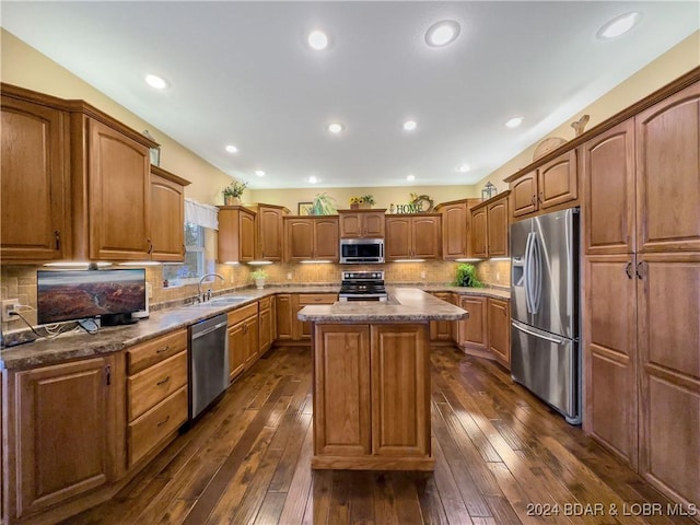 kitchen with backsplash, dark hardwood / wood-style flooring, a kitchen island, and stainless steel appliances