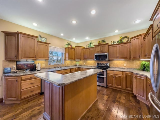 kitchen with sink, a center island, dark wood-type flooring, backsplash, and appliances with stainless steel finishes