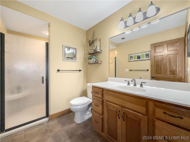 bathroom featuring vanity, a shower with shower door, and toilet