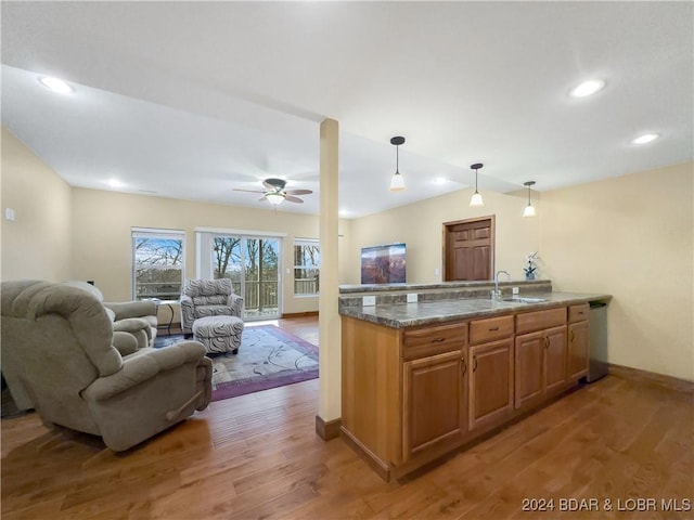 kitchen featuring pendant lighting, stone counters, sink, ceiling fan, and wood-type flooring