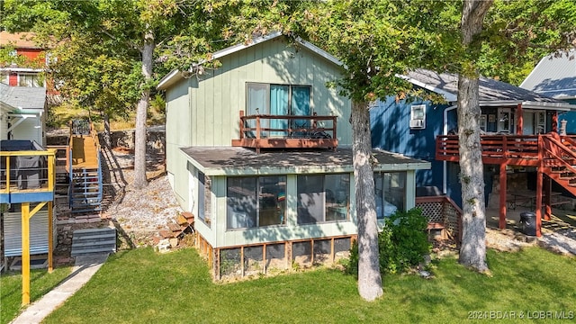 back of house with a sunroom, a balcony, and a yard