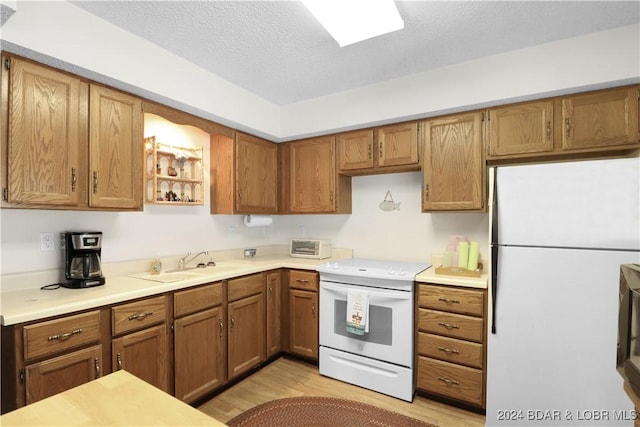 kitchen with a textured ceiling, sink, white appliances, and light wood-type flooring