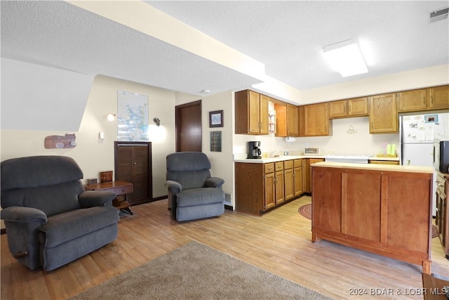 kitchen with a textured ceiling, a center island, light hardwood / wood-style flooring, and white refrigerator