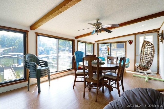 dining space featuring ceiling fan, lofted ceiling with beams, a textured ceiling, and hardwood / wood-style flooring