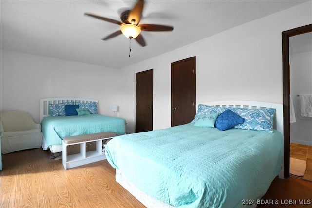 bedroom with multiple closets, ceiling fan, and hardwood / wood-style floors