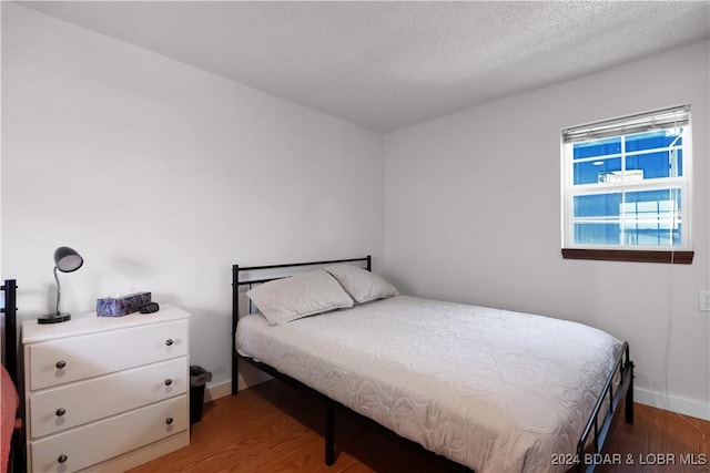 bedroom with a textured ceiling and dark wood-type flooring