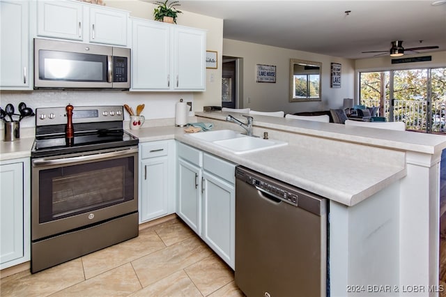 kitchen featuring white cabinetry, kitchen peninsula, stainless steel appliances, ceiling fan, and sink