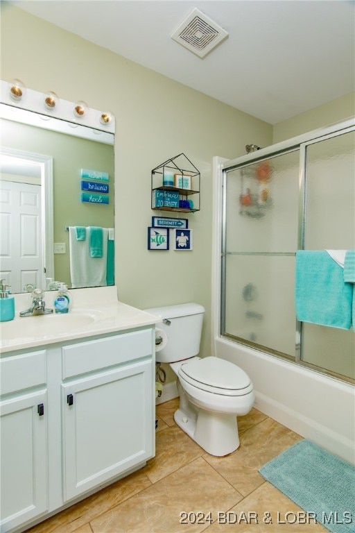 full bathroom featuring shower / bath combination with glass door, vanity, toilet, and tile patterned floors